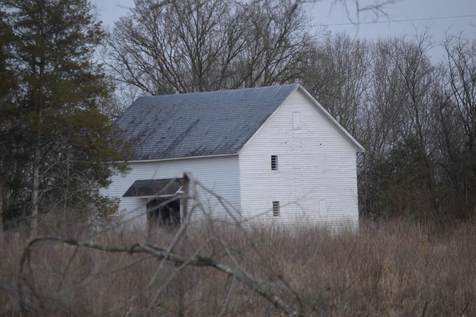 Wooden farm outbuilding in a grass field at Rivanna Farm in Fluvanna County, Virginia